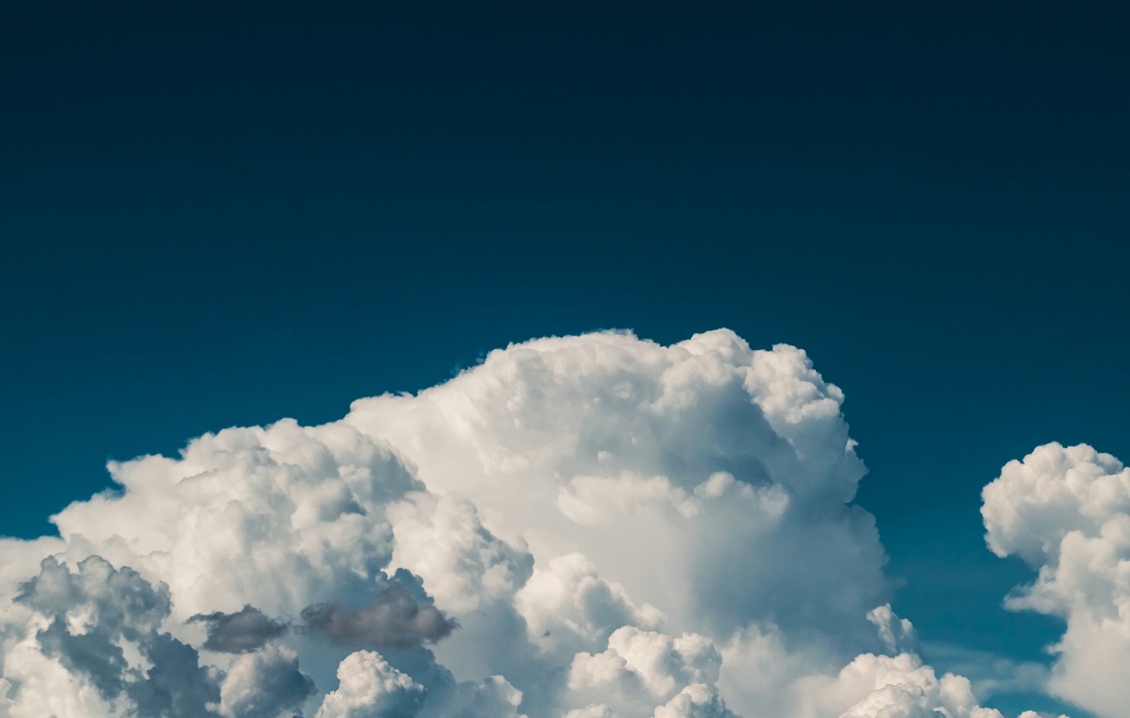 a plane flying through a cloud filled sky