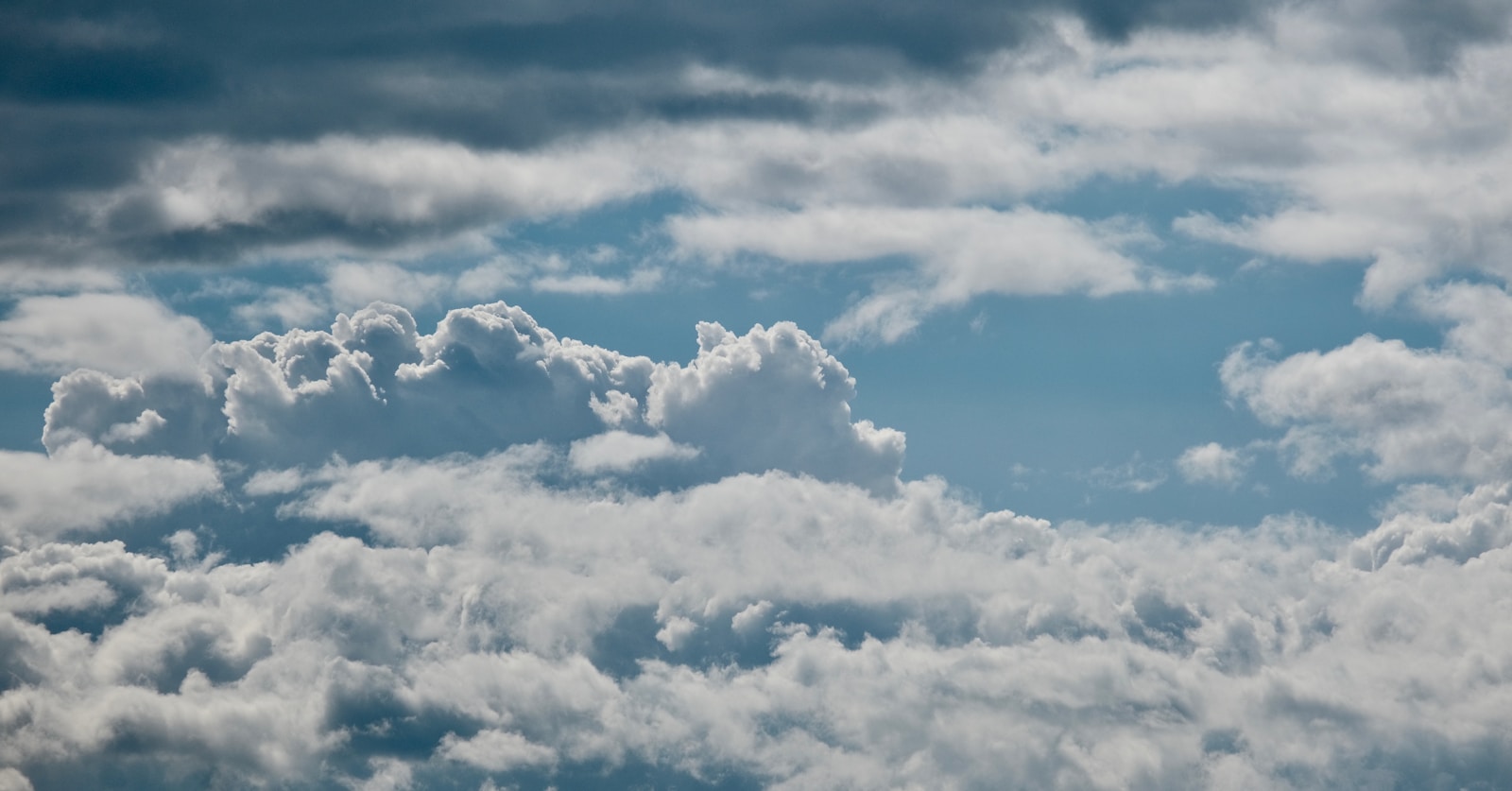 A plane flying through a cloudy blue sky — Hibrit Bulut Stratejisi: Şirket içi ve bulut arasında köprü kurma